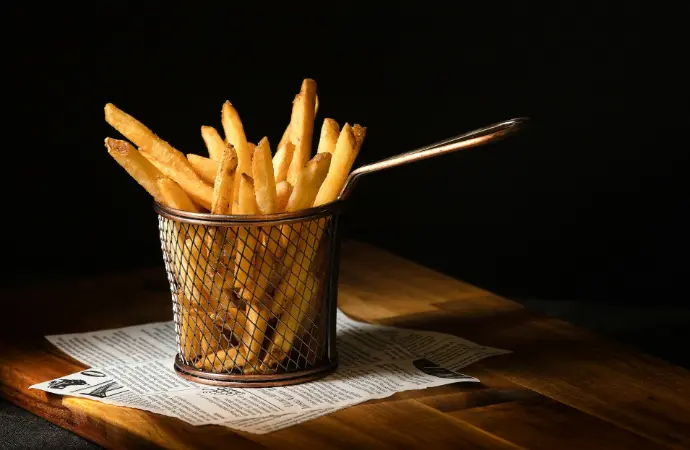 a basket of french fries sitting on top of a wooden table